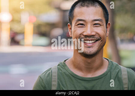 Handsome Asian man standing on a city street and smiling Stock Photo