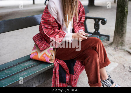 Fashionable woman sitting on bench using phone, crop Stock Photo