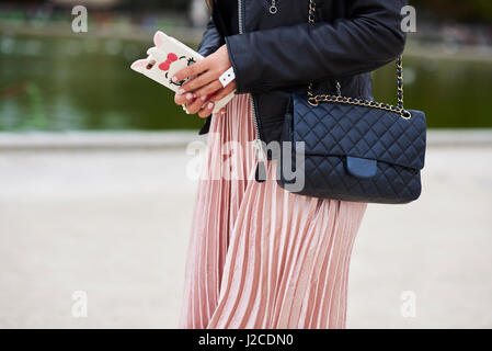 Woman in pleated skirt with designer handbag, mid section Stock Photo
