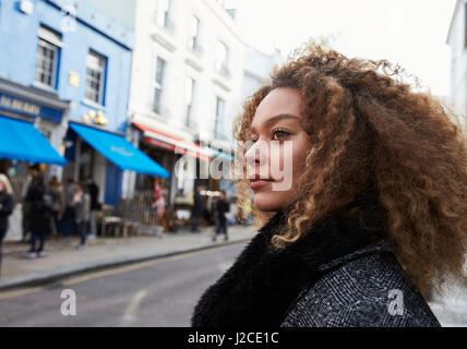 Stylish Young Woman Walking Along Busy City Street Stock Photo