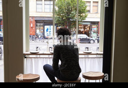 Rear View Of Young Man By Window Using Mobile Phone In Cafe Stock Photo