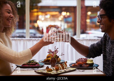 Young Couple Making Toast On Date In City Restaurant Stock Photo