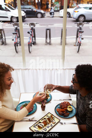 Overhead View Of Couple Making Toast On Date In Restaurant Stock Photo
