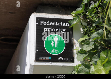 A notice on Thornhill Bridge over the Regents Canal in London warning cyclists that pedestrians have priority Stock Photo