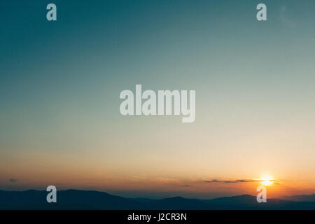 Beautiful sunset in the mountains. Added retro filter with noise Stock Photo