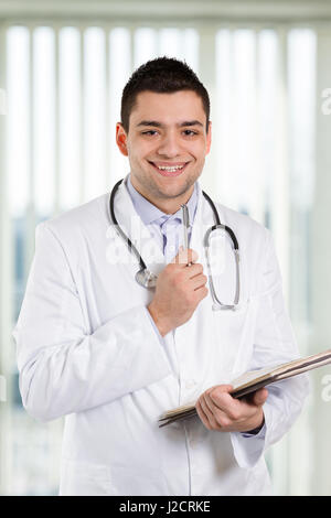 Doctor holding a pen and repotrts and smiling at you. Stock Photo