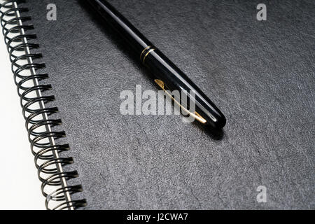 black fountain pen laying on a black ring binder Stock Photo
