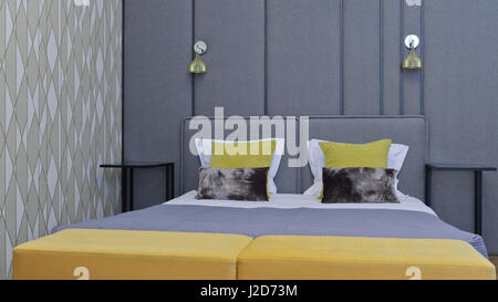 Modern luxury bedroom with king size bed, grey fabric headboard, yellow pillows . Stock Photo