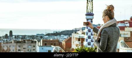 Barcelona signature style. Seen from behind young tourist woman in Barcelona, Spain in the winter with digital camera taking photo Stock Photo