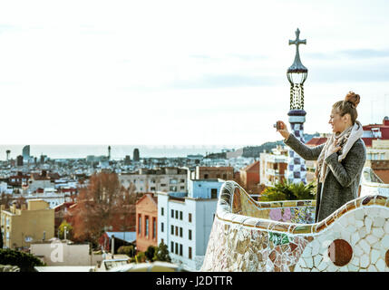 Barcelona signature style. happy young traveller woman in Barcelona, Spain in the winter with digital camera taking photo Stock Photo