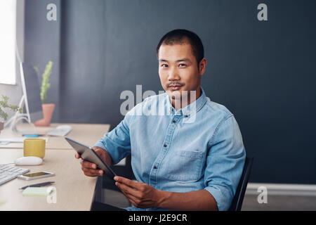 Confident Asian designer using a digital tablet at work Stock Photo