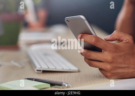 Young designer using a cellphone at his office desk Stock Photo