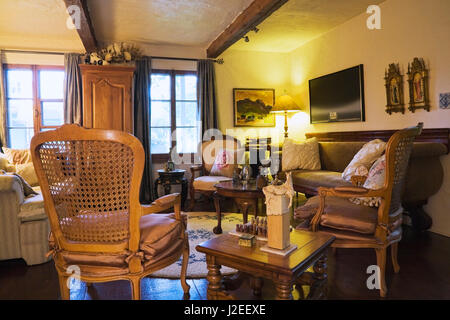 Antique wooden grid high back chairs and beige and brown sofas in the living room inside an old 1809 cottage style residential home Stock Photo