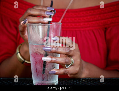 Close up of African American women's hands with beautiful manicure holding glass with ice water Stock Photo