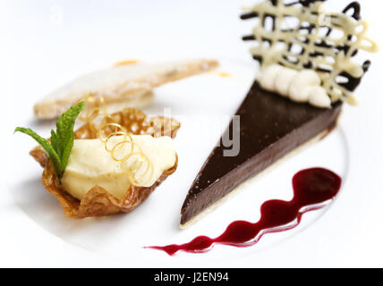 A trio of desserts; a chocolate tarte, a biscuit and a vanilla ice cream in a brandy snap basket Stock Photo