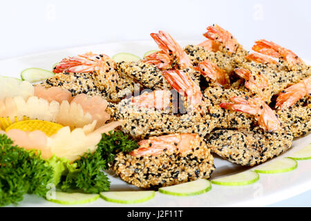 Fried shrimp with seasame and sliced cucumber on white dish Stock Photo