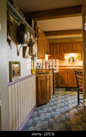 Hallway leading to rustic kitchen with wooden cabinets inside an old reconstructed 1850s cottage style log home Stock Photo