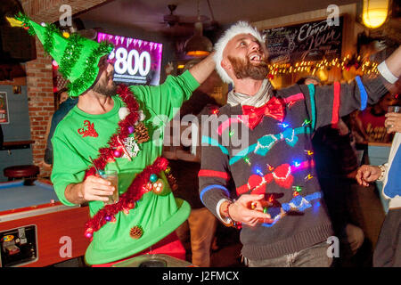 Two pool players in colorful Christmas sweaters and caps give a holiday cheer at a Newport Beach, CA, cafe. Stock Photo