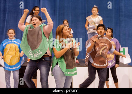 Dressed in Girl Scout cookie costumes, multiracial members of an Irvine, CA, high school dance club entertain a scout audience at the opening of the cookie selling season. Stock Photo