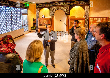 A guide shows non-Muslim local community members through a mosque on visitors day in Mission Viejo, CA. Note Arabic writing on wall and Islamic interior decoration. Stock Photo