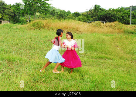 Belize, El Progreso, 2 girls in traditional dress dancing in the school garden Stock Photo