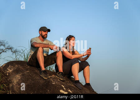 Group of tourists watching the sunset on top of the mountain. Rest after climbing. Stock Photo