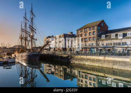 The early morning sunshine lights up a tall ship moored alongside the quay at the Barbican in Plymouth, South Devon. Stock Photo