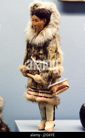 Native American artifact of an Athabaskan doll carved from wood dressed in traditional fur parka with a baby being carried inside the hood Stock Photo