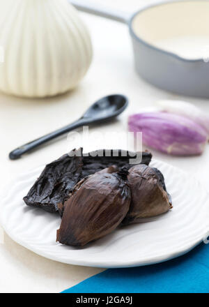 bright and colorful vertical image of black onions on a textured dish, out of focus background to ad copy space Stock Photo