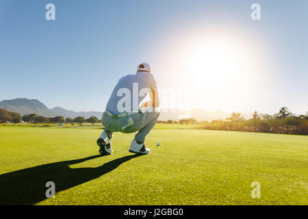 Rear view of golf player aiming shot on course. Pro golfer on field during game. Stock Photo