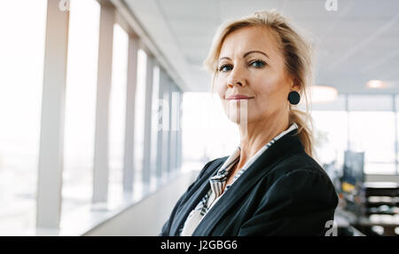 Portrait of mature businesswoman looking at camera confidently. Horizontal shot of beautiful caucasian female entrepreneur standing in office. Stock Photo