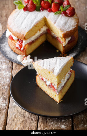 Sliced Victoria sponge cake closeup on a plate on a table. vertical Stock Photo