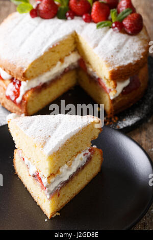 Sliced Victoria sandwich cake closeup on a plate on a table. vertical Stock Photo