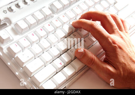 male hand typing on a white keyboard Stock Photo