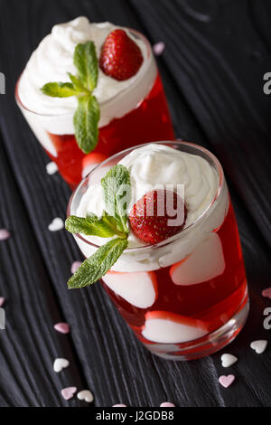beautiful strawberry cocktail with whipped cream and mint, decorated with hearts close-up on the table. vertical Stock Photo