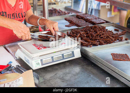GEORGE TOWN, MALAYSIA - MARCH 23: Woman weigh Chinese dried pork at the street market on March 23, 2016 on George Town, Malaysia. Stock Photo