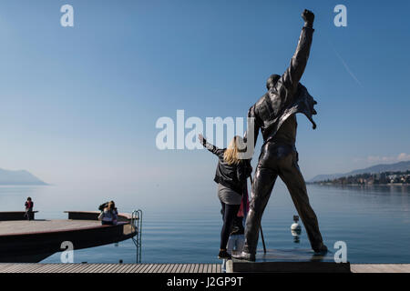 A tourist is posing for a photo with the statue of Freddie Mercury, late singer of the UK rock band Queen, at the lakefront of Lake Geneva in Montreux