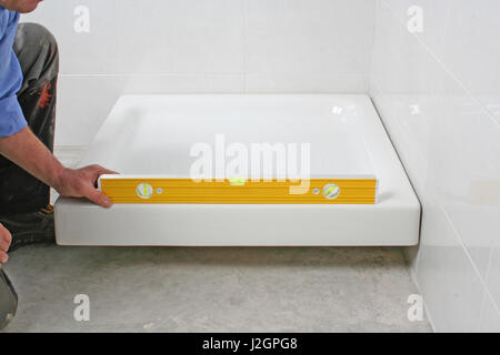 Construction worker using a spirit level for the construction of a shower basin. Stock Photo