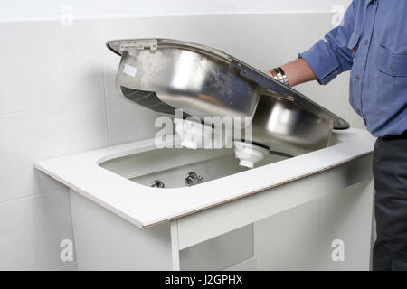 Construction worker installing a stainless steel kitchen sink Stock Photo
