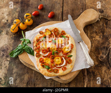 Delicious pizza with cheese, cherry tomatoes and onions on old wooden background Stock Photo