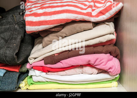 A stack of knitted warm woolen clothes in wardrobe close up Stock Photo