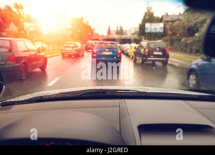 Driving a car in bad weather conditions in traffic jam towards sunrise - blurred view Stock Photo
