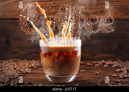 Coffee lettering, Levitating text from coffee beans with steam and splashes from a cup on a wooden background of strewn with coffee beans Stock Photo