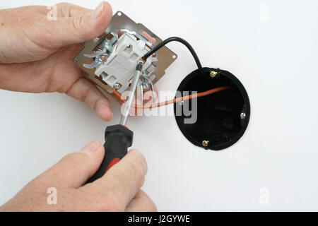 Electrician installing a light switch in a wall socket Stock Photo