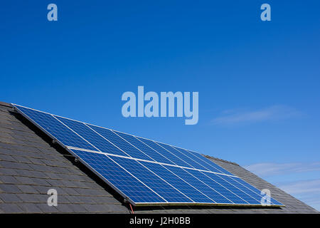 Solar panels on house roof with blue sky in background,North Wales,Uk.Solar power,renewable energy source,environmental friendly energy production,Uk. Stock Photo