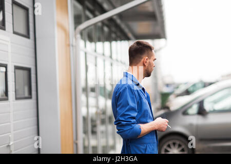 auto mechanic smoking cigarette at car workshop Stock Photo