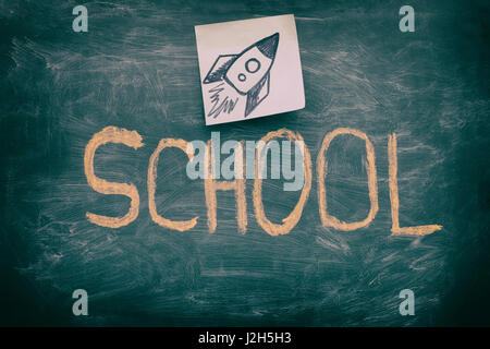 Word School on green chalkboard background and rocket on a paper note. Close up. Stock Photo
