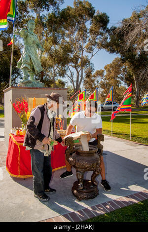 A local Vietnamese American gets some help from a Hispanic neighbor in setting up his shrine at the statue of Tran Hung Dao (1226-1300), Supreme Commander of Vietnam during the Tran Dynasty in a Lunar New Year or Tet celebration in a Fountain Valley, CA, park. Stock Photo