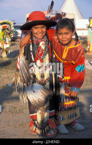 Two young pow wow buddies dressed in traditional regalia are arm in arm at a pow wow both dressed in traditional regalia Stock Photo
