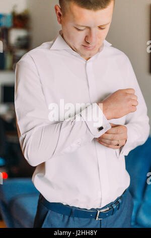 Elegant young fashion man in white shirt fixing his cufflinks. Stock Photo